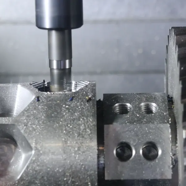 Nahaufnahme einer CNC-Fräsmaschine, die ein Metallwerkstück fräst, mit sichtbaren Zahnrädern und sechseckigen Mustern auf der Oberfläche, die während des Bearbeitungsprozesses Metallspäne erzeugen.